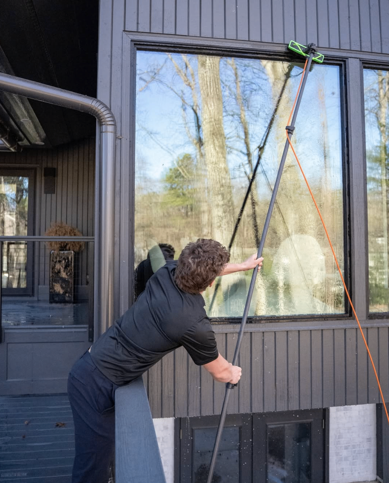Equinox technician cleaning a large window with a water-fed pole